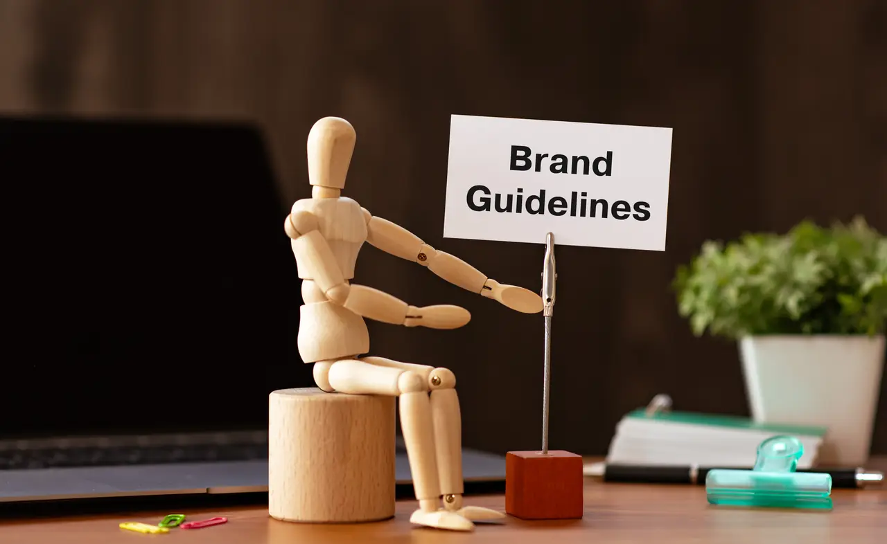 Wooden artist figure presenting a sign labeled Brand Guidelines