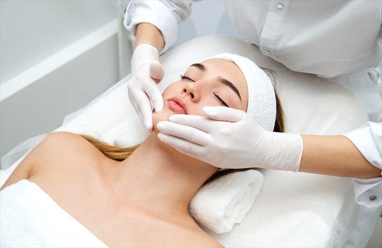 Practitioner wearing gloves examining a client's face