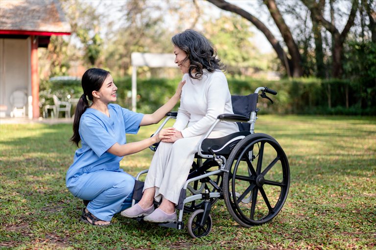 Caregiver speaking with a woman seated in a wheelchair