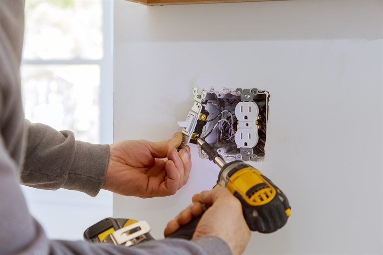 Electrical contractor installing a light switch beside an outlet