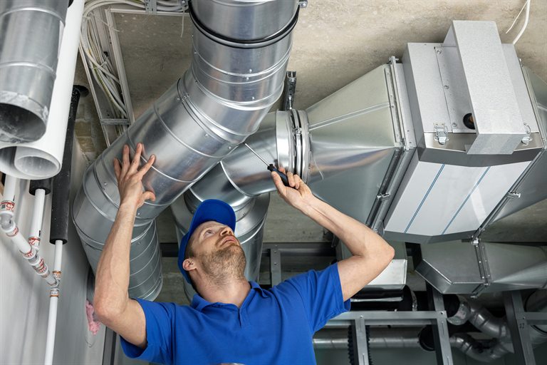 HVAC technician inspecting metal ductwork