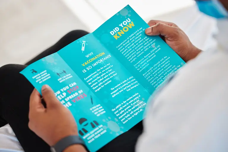 Person holding a folded informational brochure