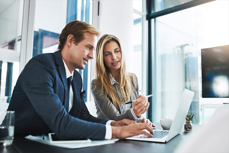 Two business consultants reviewing work on a laptop