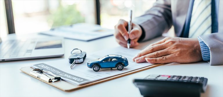 Insurance agent completing paperwork beside a model car and keys