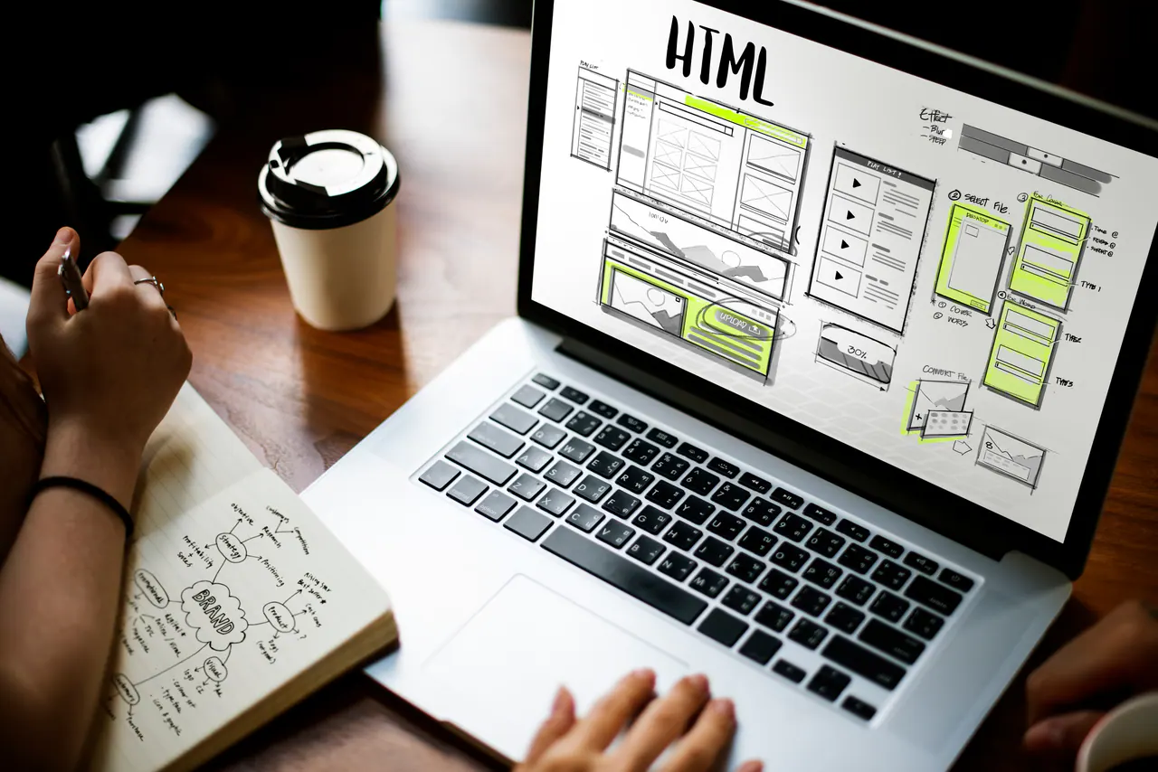 Website wireframes displayed on a laptop beside planning notes